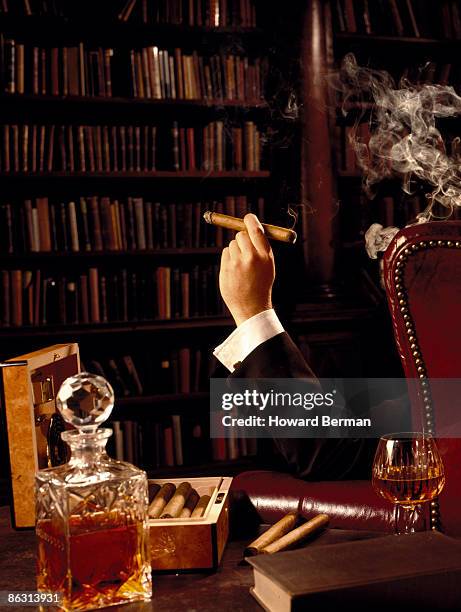 man smoking cigar in library - cigar stock-fotos und bilder