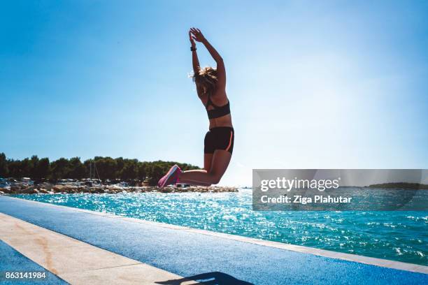 fit woman jumping in the air at the beach - slovenia beach stock pictures, royalty-free photos & images