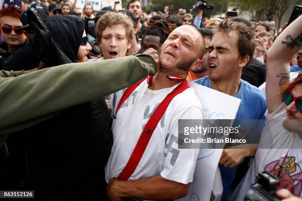 Man wearing a shirt with swastikas on it is punched by an unidentified member of the crowd near the site of a planned speech by white nationalist...