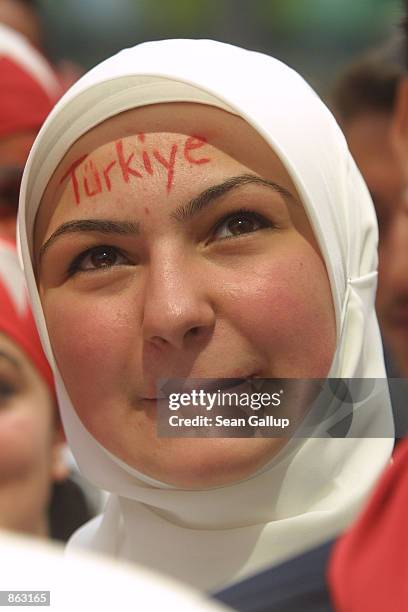 Turkish woman wearing a headscarf watches Turkey play Brazil in World Cup soccer semi-finals on a large screen TV June 26, 2002 in central Berlin,...