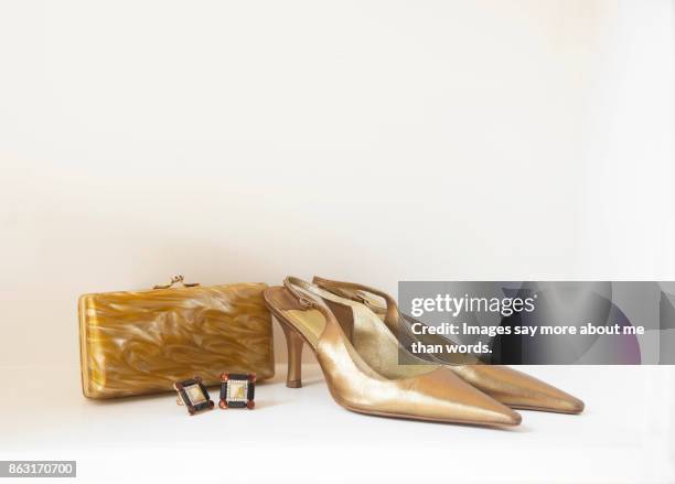 pair of golden shoes, golden clutch and earrings. - gold purse stock-fotos und bilder