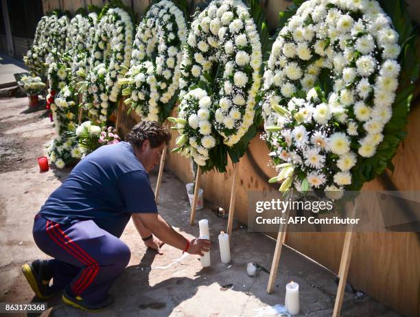 Man places candles under a group of wreaths for the victims of Mexico's September 19 earthquake, during a tribute in their memory in front of a...