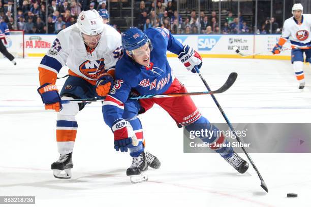 Adam Cracknell of the New York Rangers skates with the puck against Casey Cizikas of the New York Islanders at Madison Square Garden on October 19,...