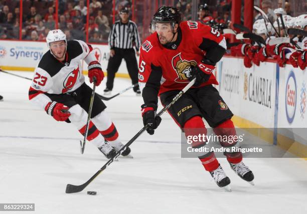 Cody Ceci of the Ottawa Senators stickhandles the puck as Stefan Noesen of the New Jersey Devils pressures on the forecheck at Canadian Tire Centre...