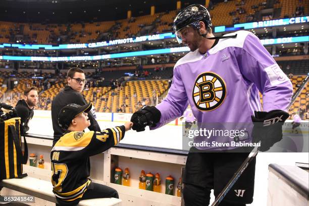 Adam McQuaid of the Boston Bruins wears a Hockey Fights Cancer jersey and fists bumps Liam Fitzgerald the fist bump kid before the game against the...