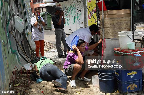 Venezuelans take cover from tear gas and rubber bullets shot by riot police during clashes with opposition demonstrators in downtown Caracas during...