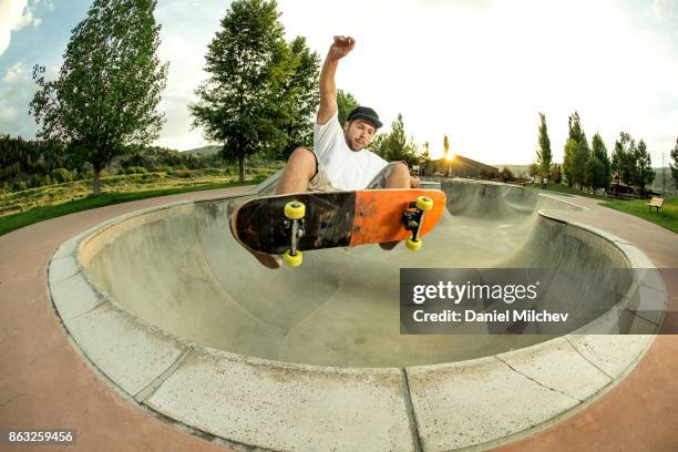 kid with a snowboard jumping out of a skate park bowl. - skateboard rampe stock-fotos und bilder