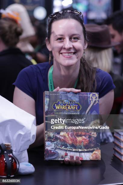 Waist up portrait of cookbook author and historical food expert Chelsea Monroe-Cassel holding a book about World of Warcraft cooking at the Jacob...