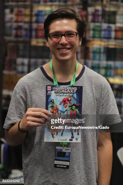 Waist up portrait of male comic book fan holding up a comic book and smiling during New York Comic Con at the Jacob Javits Convention Center in New...
