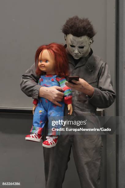 Three quarter length portrait of a comic book fan dressed as the character Chucky, holding a doll and texting on a cellphone during New York Comic...