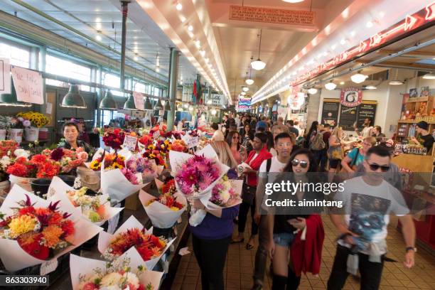 tourists and shoppers inside the famous pike place market - pike place market flowers stock pictures, royalty-free photos & images