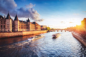Dramatic sunset over river Seine in Paris, France, with Conciergerie and cruise boats.