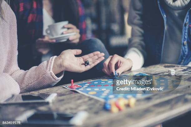 drei mädchen spielen zusammen ein gesellschaftsspiel. auf seite konzentrieren. - spieleabend stock-fotos und bilder