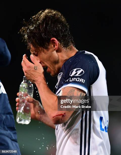 Melbourne's Mark Milligan reacts after being sandwiched between Adelaides Vince Lia and Melbourne's Leigh Broxham defending a goal and leaves the...