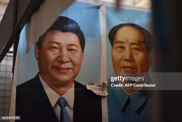 This photo taken on September 19, 2017 shows painted portraits of Chinese President Xi Jinping and late communist leader Mao Zedong at a market in...