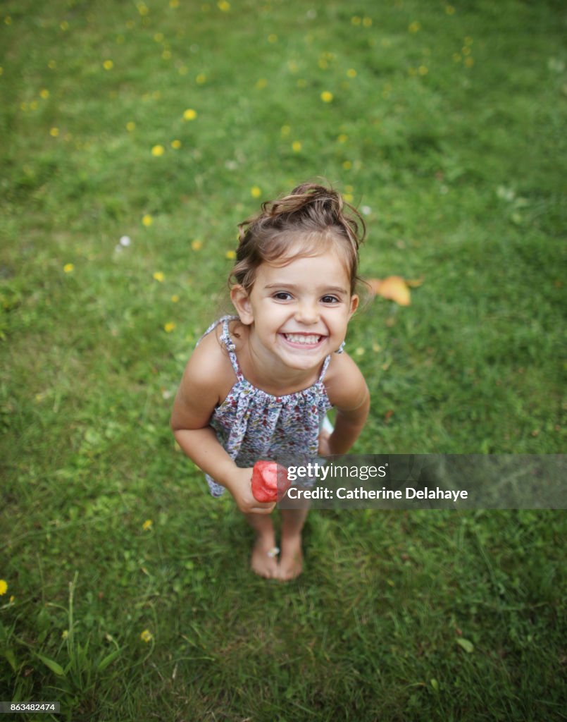 A 3 years old girl eating icecream in the garden