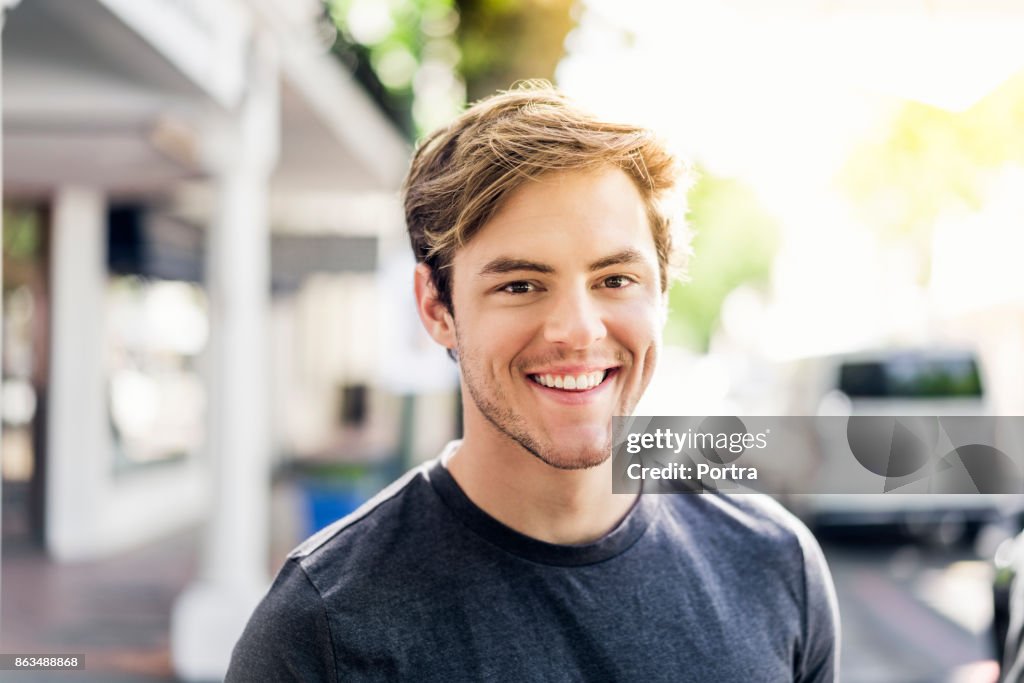 Portrait de souriant jeune homme dans la ville de jour ensoleillé