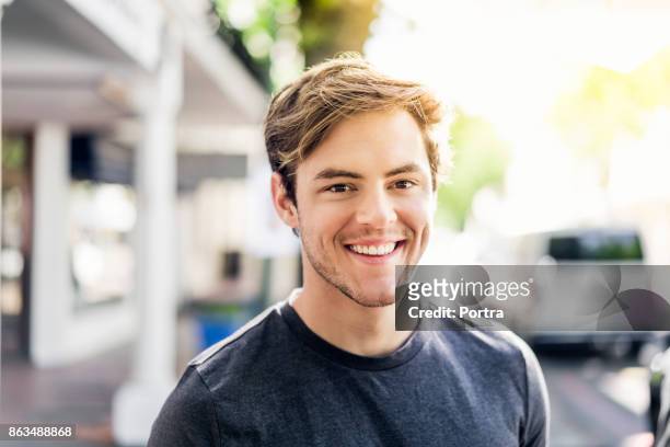 portrait of smiling young man in city on sunny day - white caucasian stock pictures, royalty-free photos & images