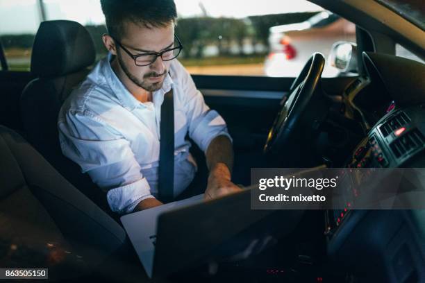 man using laptop in car - motor vehicle stock pictures, royalty-free photos & images