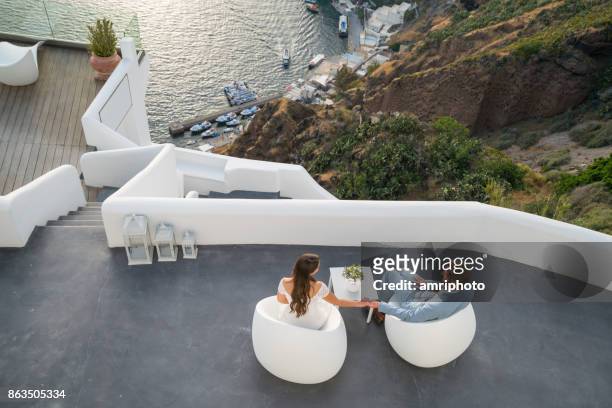 authentic wealth - couple sittging on terrace on santorini island - europe bride stock pictures, royalty-free photos & images