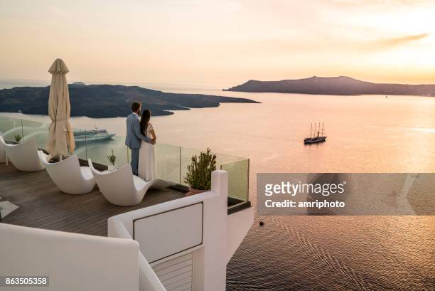 authentic wealth - coppia ricca in piedi sulla terrazza con una splendida vista sul mare - greece foto e immagini stock