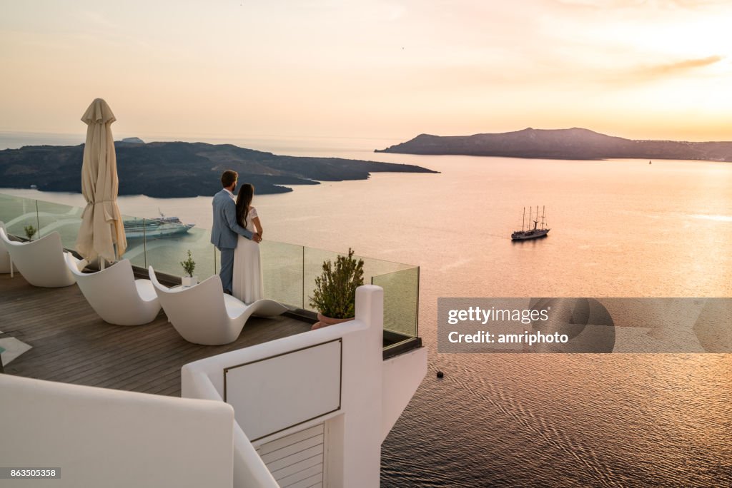 Authentic Wealth - rich couple standing on terrace with amazing sea view