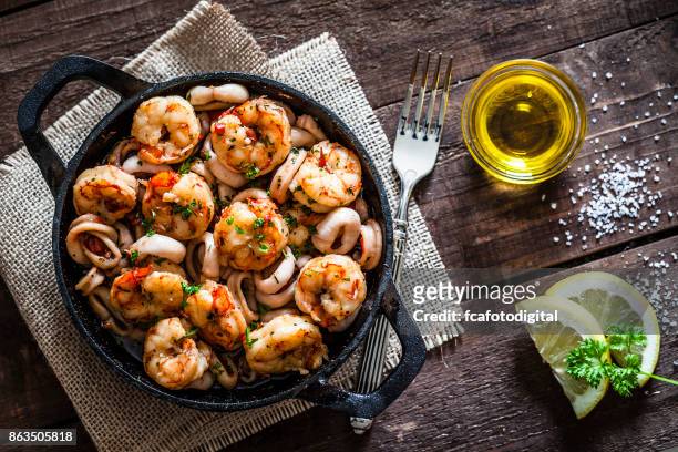 gamberi e anelli di calamari cotti su padella di ghisa - shrimp foto e immagini stock