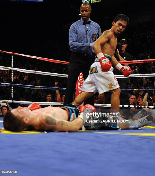 Manny Pacquiao of the Philippines looks at Ricky Hatton of England laying on the ring in the second round of their Junior Welterweight title fight at...