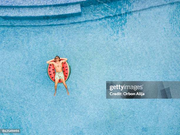 man relaxing at swimming pool - lilo stock pictures, royalty-free photos & images