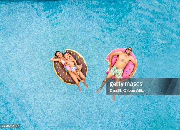 family relaxing at swimming pool - pool raft stock pictures, royalty-free photos & images
