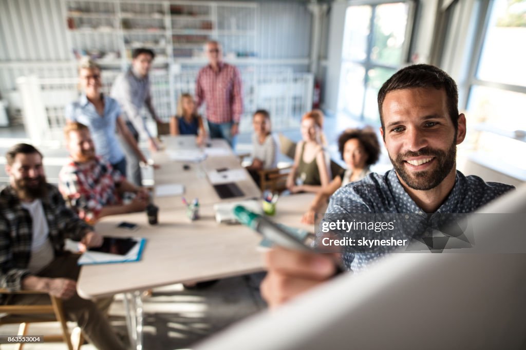 Happy businessman writing on whiteboard during business presentation in the office.