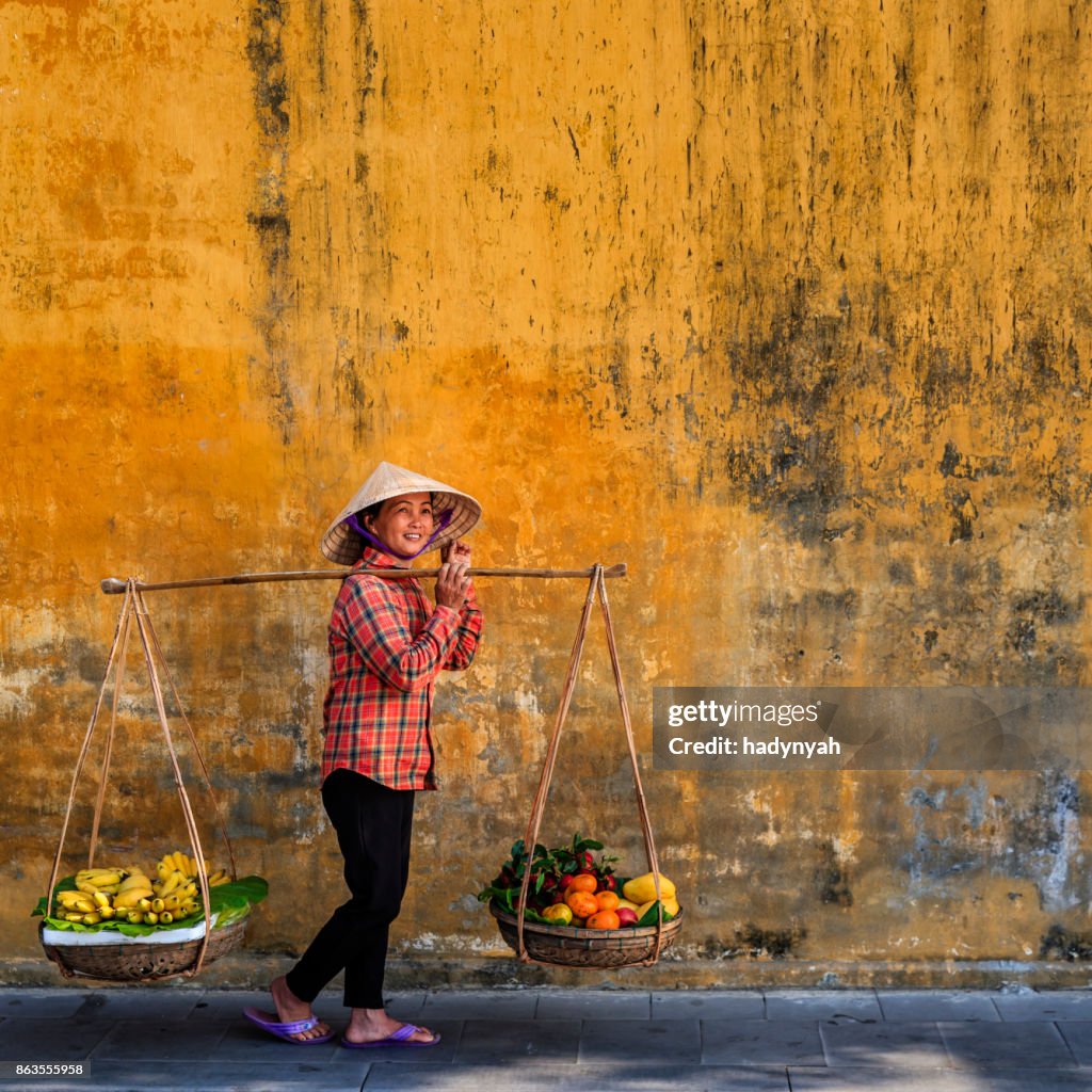 Vietnamese woman selling tropical fruits, old town in Hoi An city, Vietnam