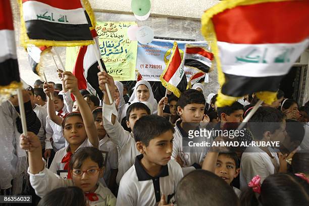 Sunni and Shiite Muslim orphans wave the national flags during a reconciliation gathering between orphans from the Shiite Kadhimiyah district on the...