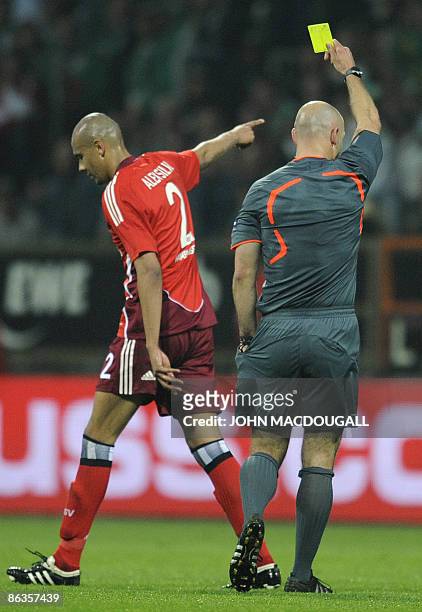 Hamburg's Brazilian defender Alex Silva is shown a yellow card by referee Howard Webb of England during the UEFA Cup semi-final football match Werder...