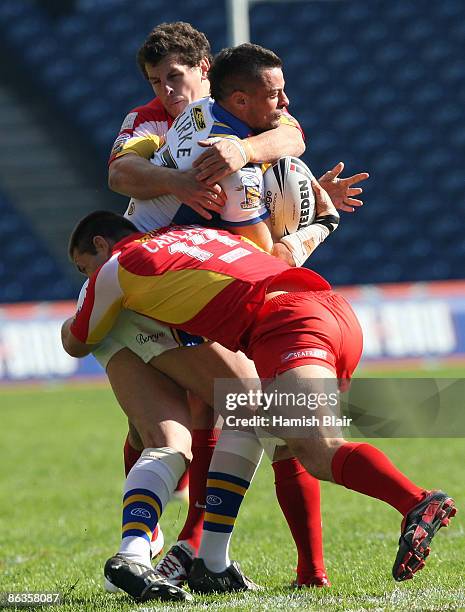 Ian Kirke of Leeds is tackled by Greg Bird and Dane Carlaw of Catalans during the Super League Magic Weekend match between Catalans Dragons and Leed...