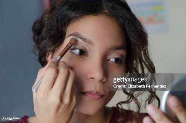 young woman applying eyeshadow to her brow bone - eyeshadow photos et images de collection