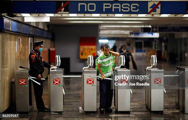 Police officer wears a surgical mask, to help prevent being infected with the swine flu, as the watches the turnstiles in the subway system on May 3,...