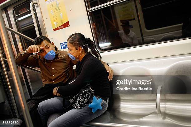 Two people ride the subway wearing surgical masks, to help prevent being infected with the swine flu on May 3, 2009 in Mexico City, Mexico. The...