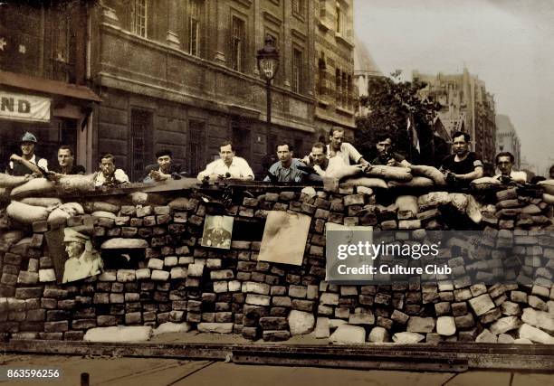 Paris Liberation, 1944. Barricades at Rue Saint-Jacques, Paris. Men stand behind a street barricade adorned with pictures, including one of Hitler.