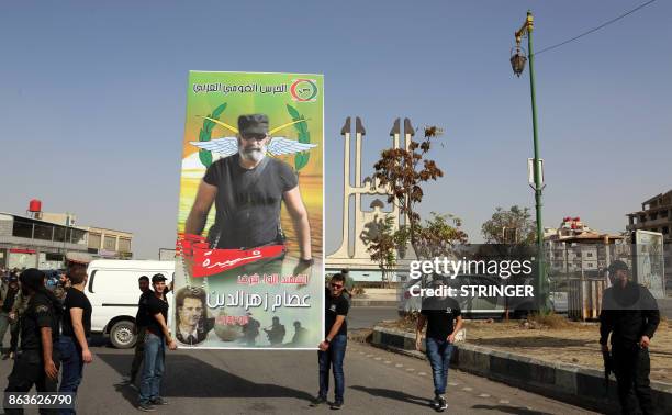 Syrians carry a banner showing a picture of Brigadier General Issam Zahreddine during his funeral in the southern city of Suwaida on October 20,...