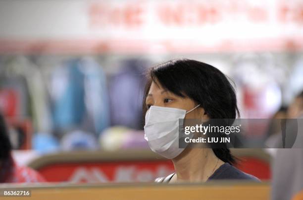 Masked woman browses clothes at a shop in Beijing on May 4, 2009. Mexico said its swine flu, known officially as "influenza A, had peaked and was now...