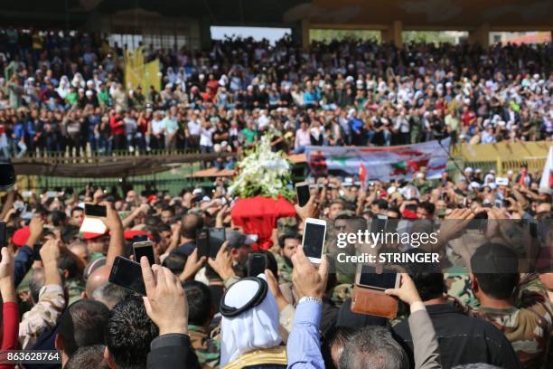 Syrians use their cell phones to take pictures of the coffin of Brigadier General Issam Zahreddine at a stadium during his funeral in the southern...