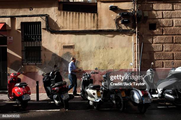 Man carrying trays of eggs walks past a row of scooters on October 20, 2017 in Barcelona, Spain. The Spanish government is to take steps to suspend...