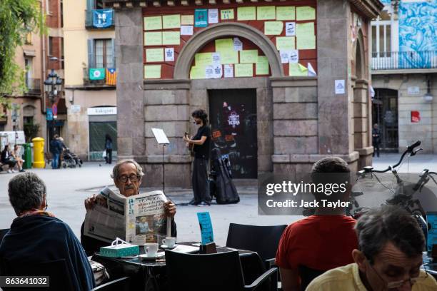 Man reads a newspaper in a square as a busker performs on October 20, 2017 in Barcelona, Spain. The Spanish government is to take steps to suspend...