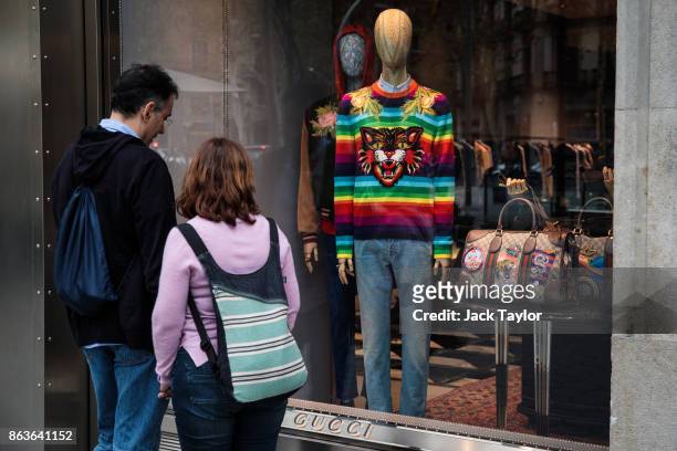 Couple look at outfits on display in the window of a Gucci shop on October 20, 2017 in Barcelona, Spain. The Spanish government is to take steps to...