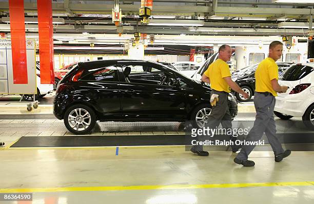Employees of German carmaker Adam Opel GmbH walk past an Opel Corsa at a plant on May 4, 2009 in Eisenach, Germany. Representatives of the German...