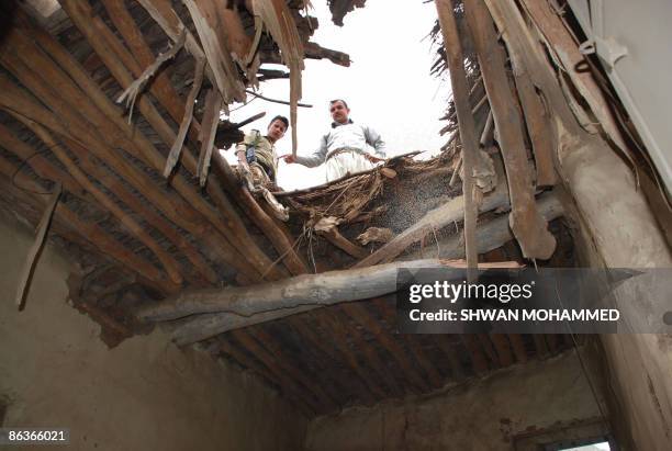Kurdish men look down at the shell damage to a roof following an Iran attack on Narmalas, 165 kms from the northern city of Sulaimaniyah close to the...