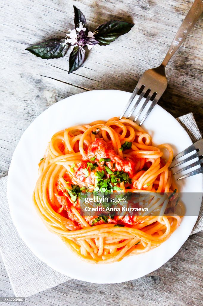 Spaghetti with vodka sauce topped with freshly grated parmesan cheese and fresh parsley on a plate, directly above view