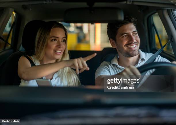 couple driving and using a gps while pointing their way - couple pointing imagens e fotografias de stock