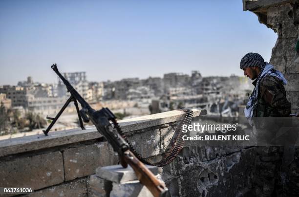 Fighter of the Syrian Democratic Forces stands guard on a rooftop in Raqa on October 20 after retaking the city from Islamic State group fighters....